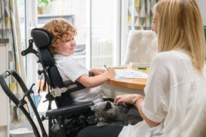 Mid adult mother and disabled 6 year old son in dining room, face to face, smiling and cheerful