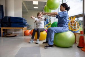 Physicia training a female patient in rehabitation clinic